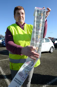 Une Gilet Jaune tient du papier toilette à l’effigie de Macron