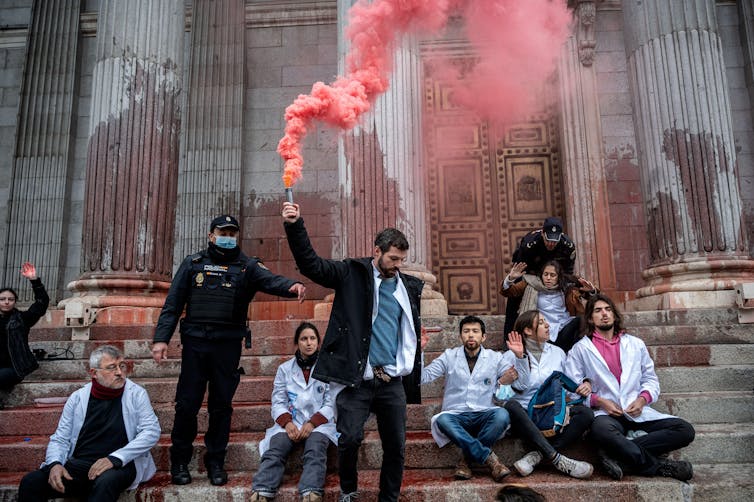 Protesters with red flare in front of old building