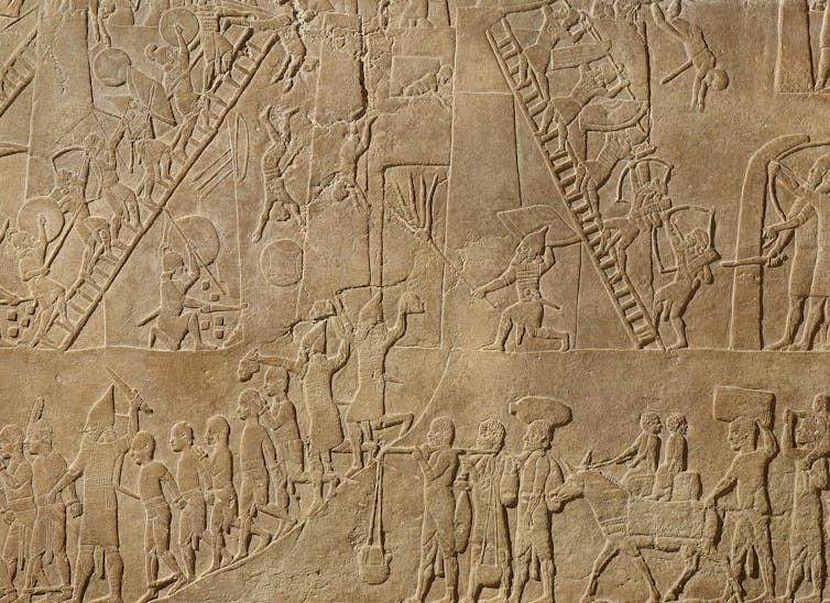 An engraving shoes Assyrian fighters climbing ladders, engaged in combat and digging tunnels under a fortification.