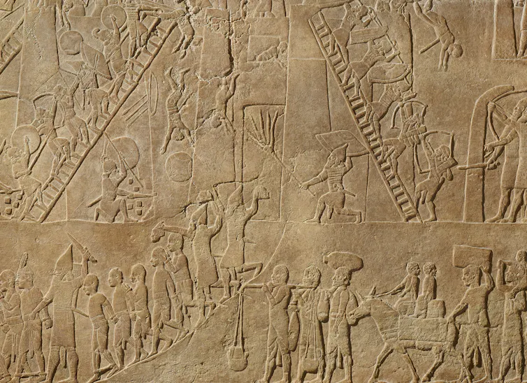 An engraving shoes Assyrian fighters climbing ladders, engaged in combat and digging tunnels under a fortification.