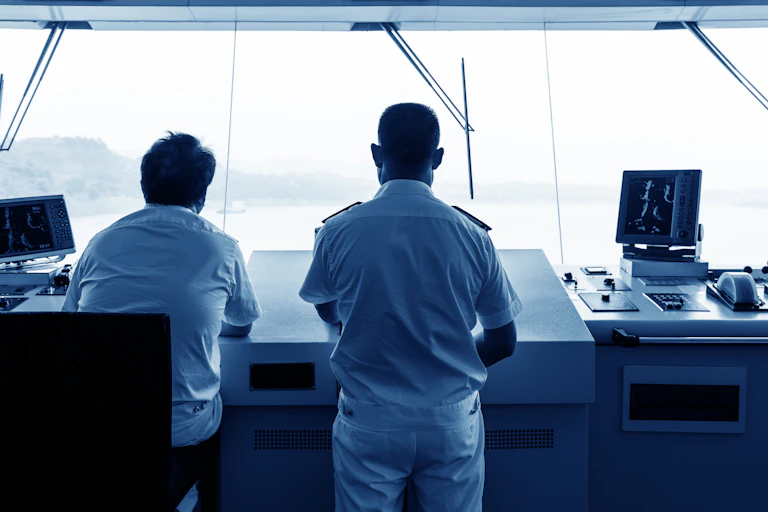 Backs of two sailors sailing a ship