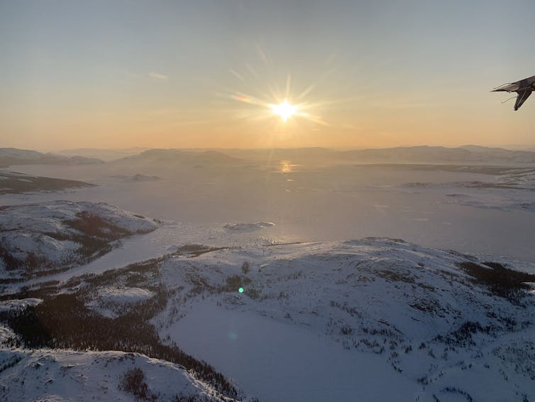 The sun low on the horizon above a snowy landscape