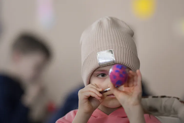 Un enfant peint un œuf de pâques