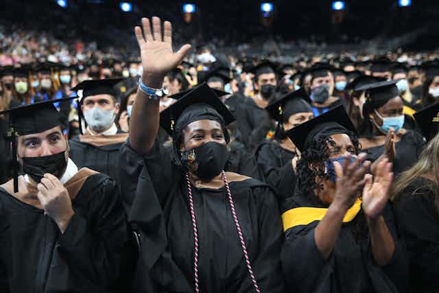 A class of college students wear black gowns at their graduation ceremony.