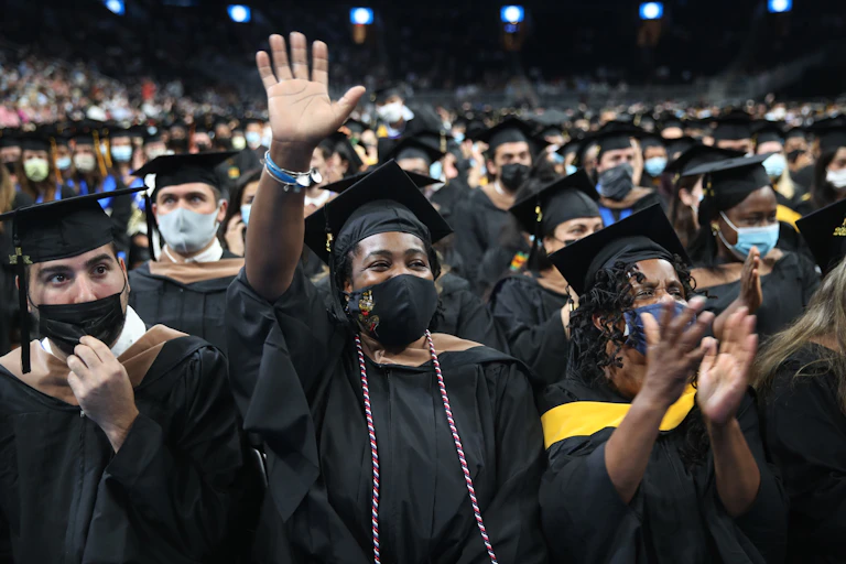 A class of college students wear black gowns at their graduation ceremony.