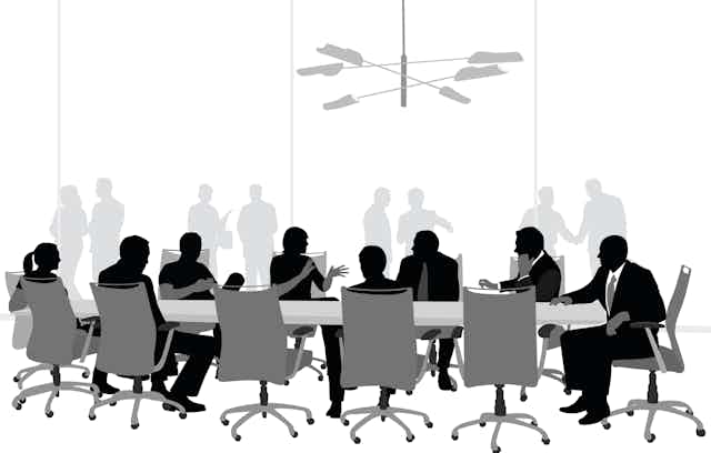A vector silhouette illustration of a business meeting in a conference room with business men and women sitting around a table with people behind a glass window in the background.
