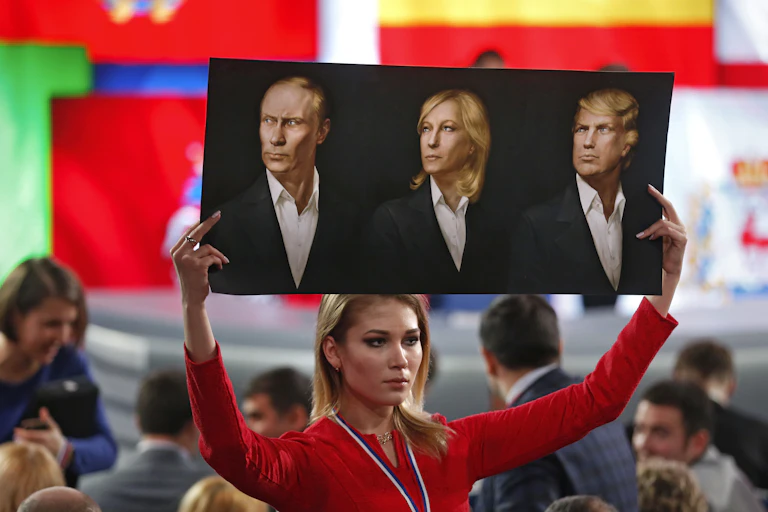 A woman holds up a poster showing Vladimir Putin, Marine Le Pen and Donald Trump.