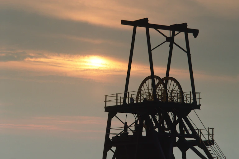 Coal mine gear against sunset sky