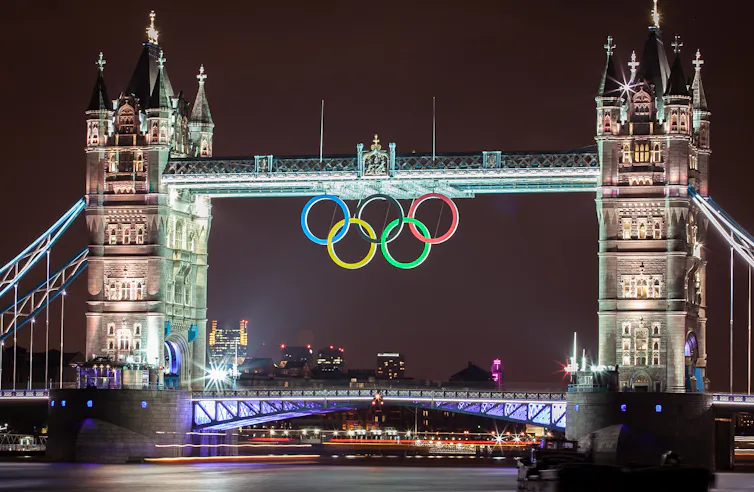 Tower Bridge in London at night with olympic rings hanging from it.