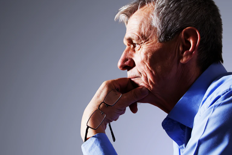 Older man in a shirt thinking to himself