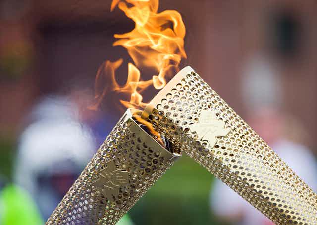 The Olympic Flame is passed from one torch to the next.