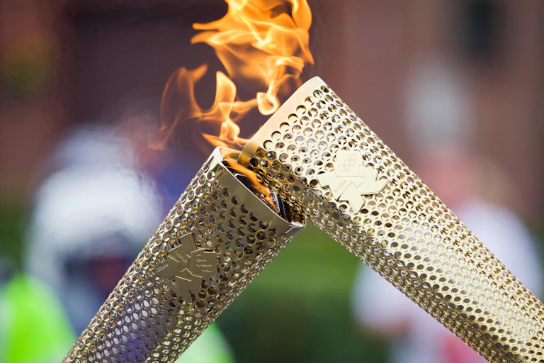 The Olympic Flame is passed from one torch to the next.
