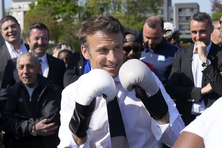 Emmanuel Macron porte des gants de boxe alors qu’il rencontre un boxeur local lors d’une visite de campagne à Saint-Denis, en banlieue parisienne le 21 avril 2022