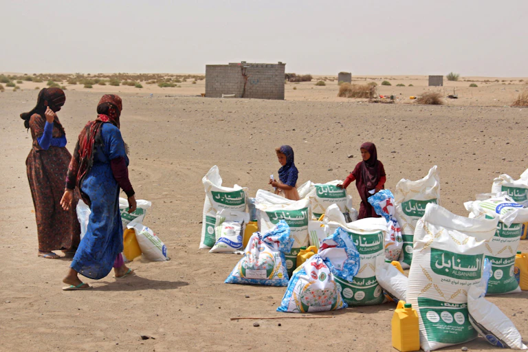 Women choose bags of flour and jugs of cooking oil