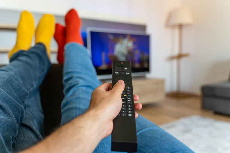 Young couple changing channels while relaxing on sofa at home.