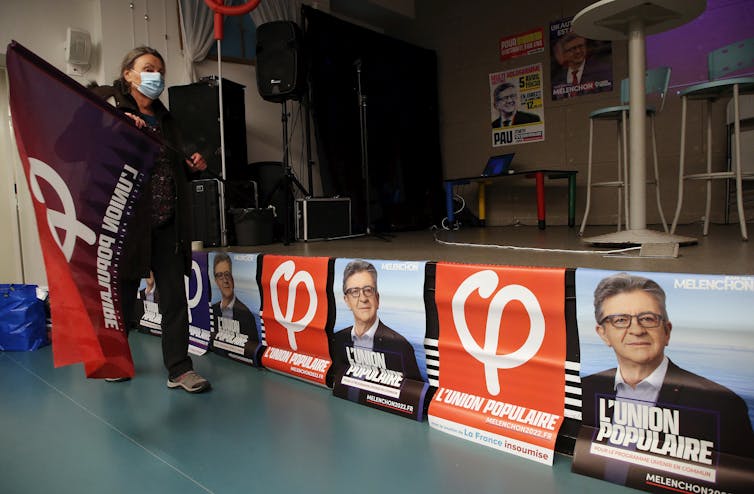 Une femme passe devant des affiches de Jean-Luc Melanchon