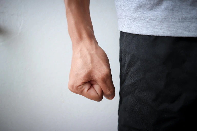 A mans fist is clenched against his thigh