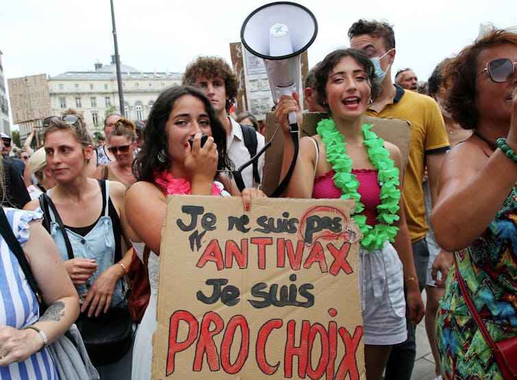 Des jeunes femmes portent une pancarte et un porte-voix lors d’une manifestation