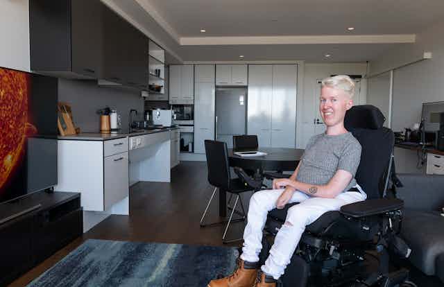 Young man sitting in wheelchair inside a new accessible apartment