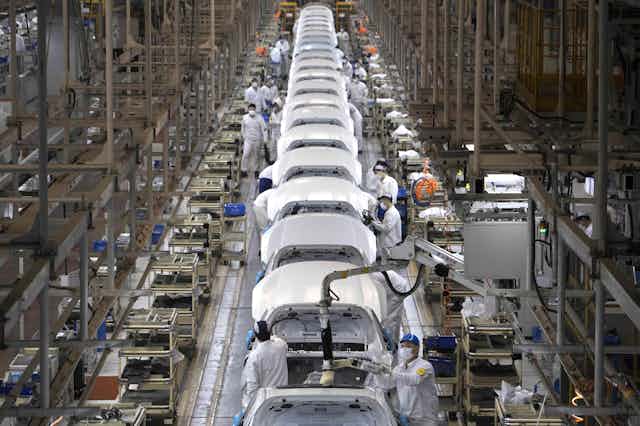 A photo showing a production line full of partly-assembled cars and several workers.