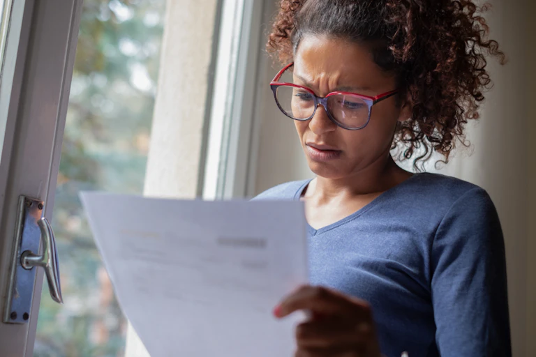 Worried woman holding piece of paper