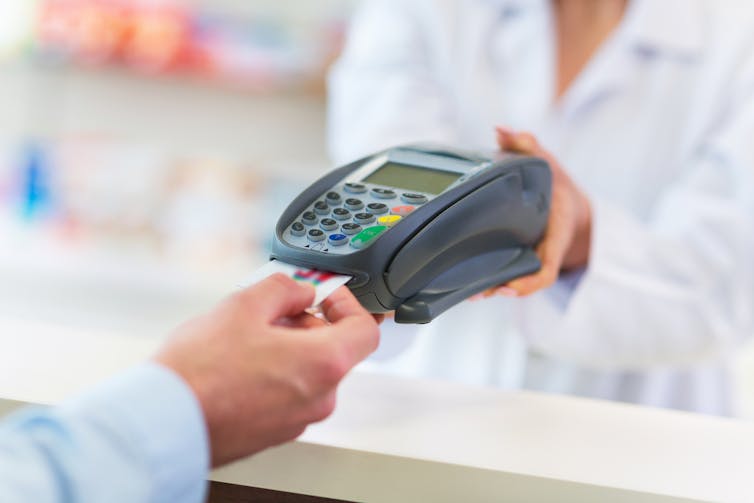 Person using EFTPOS machine in pharmacy or clinic