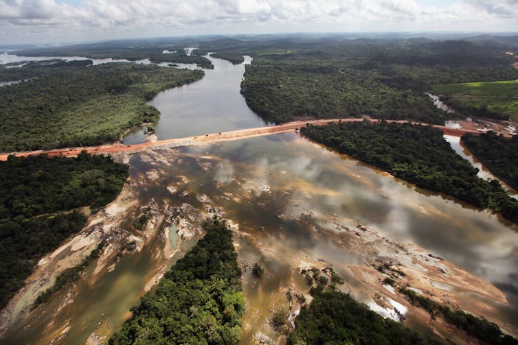 Wide aerial view of Amazon rainforest and the dam under construction.