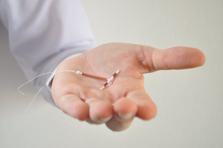 Hand holding a copper IUD