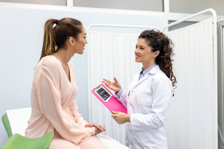 Nurse chatting to young female on doctor's bed