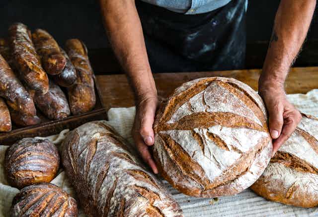 Gros plan sur les mains d'un boulanger qui présentent ses pains