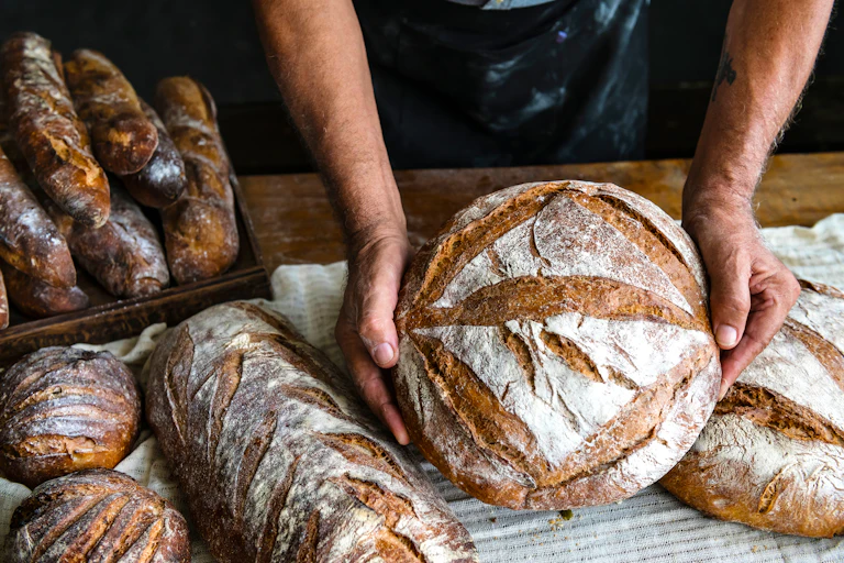Gros plan sur les mains d'un boulanger qui présentent ses pains