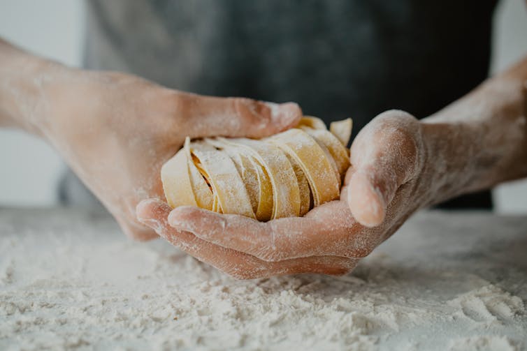 Gros plan sur des mains qui préparent des pâtes