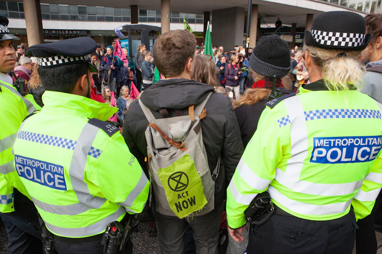 Rear view of an extinction rebellion protest, with one protester standing between two police officers