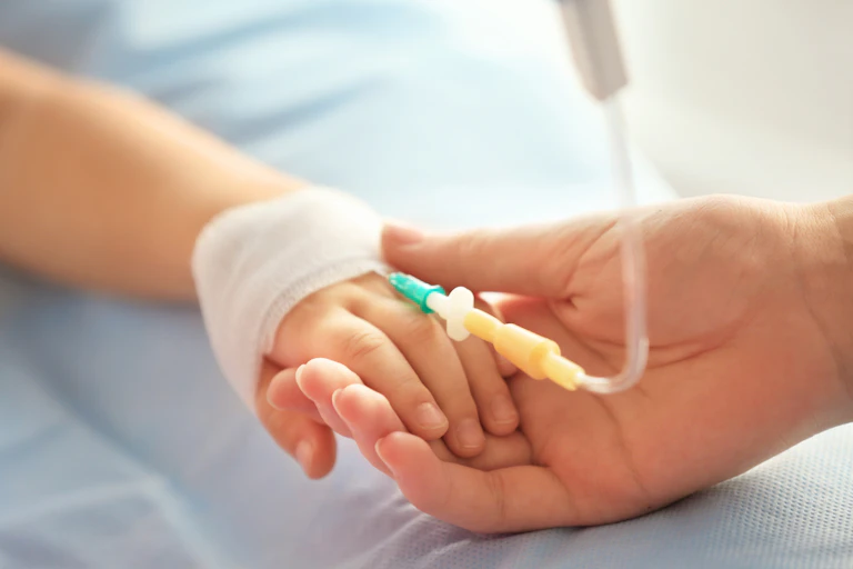 Child's hand with a catheter in it.