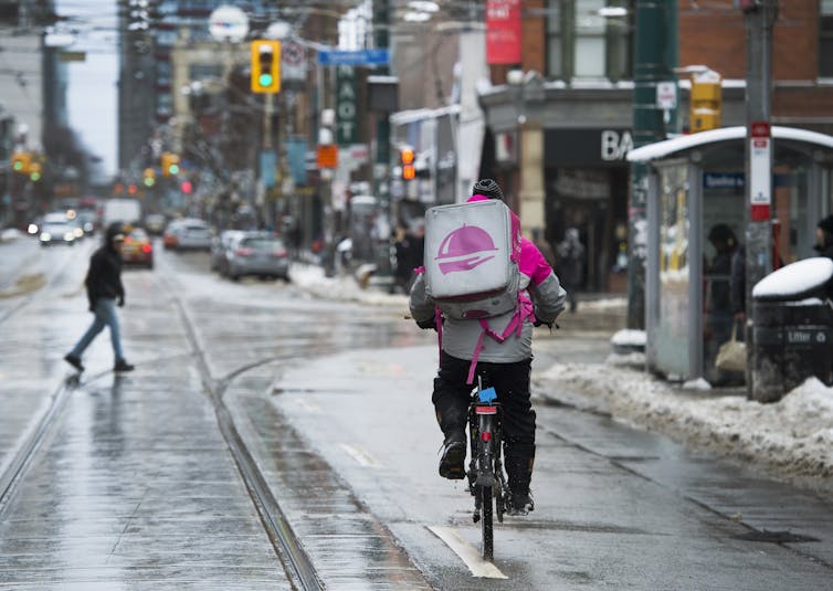 a food delivery bike rider cycling down a city street in winter