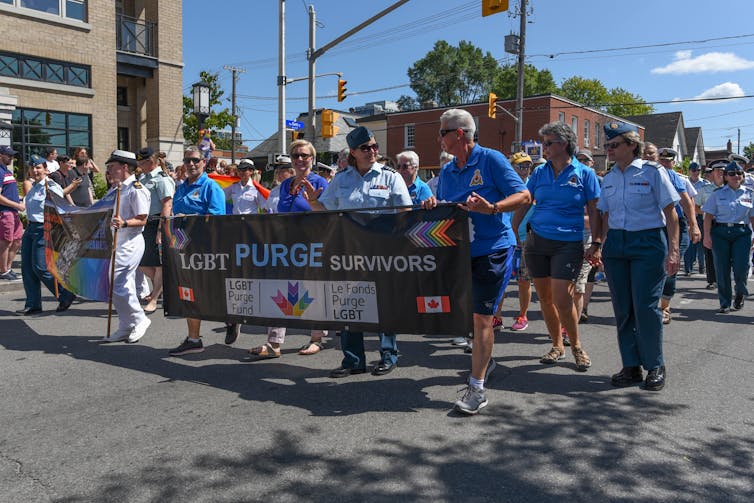 A group of people in marching in a parade holding a bannar