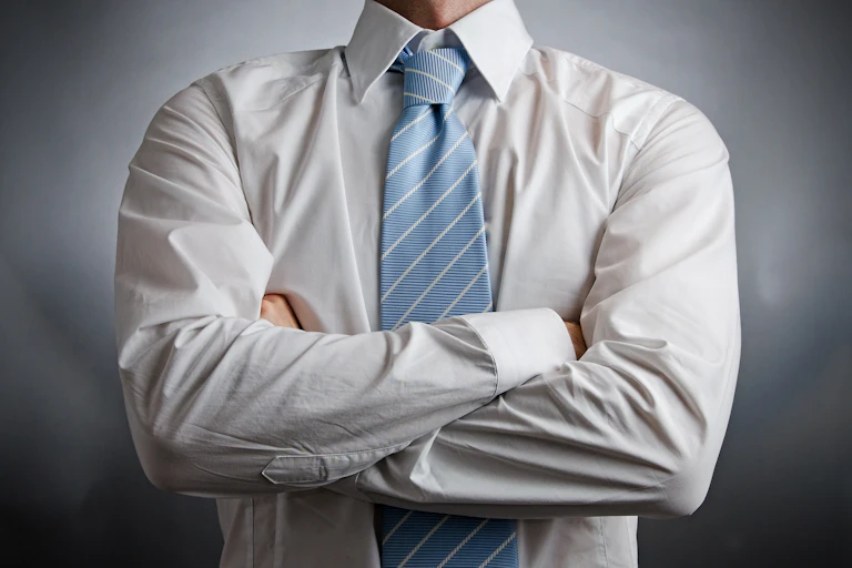 Someone in a dress shirt and tie with their arms crossed