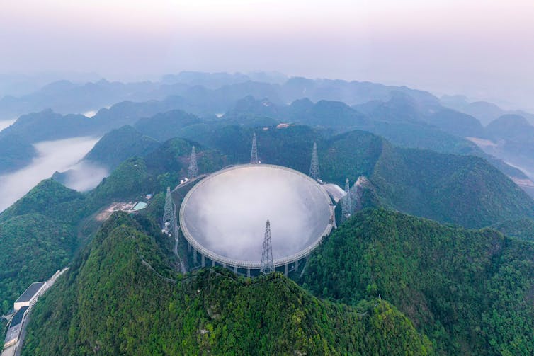 Teleskop berbentuk piring bola besar di puncak gunung.