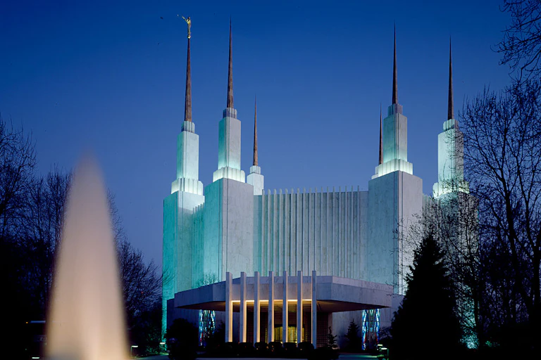A white building with six tall spires behind a fountain.