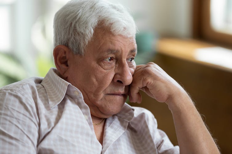 Elderly man leaning on fist, looking worried