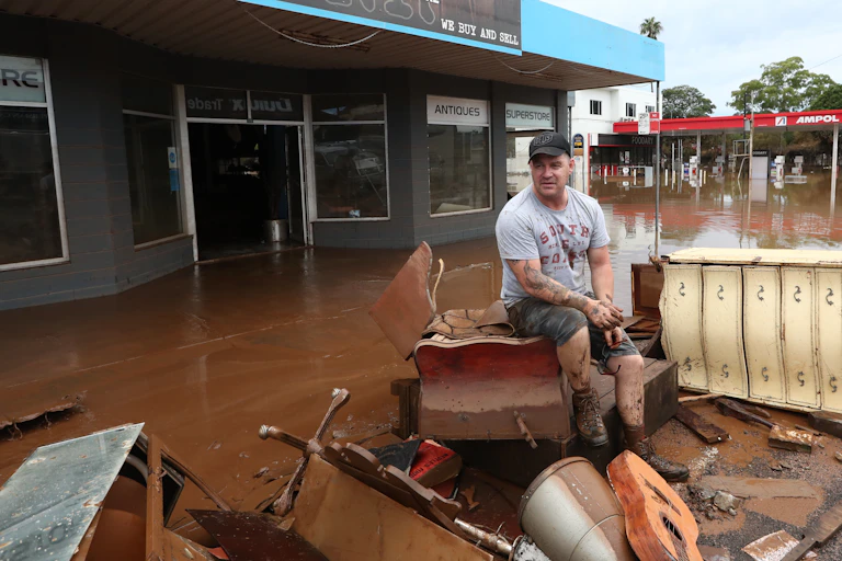 man sits on ruined furniture on flooded street