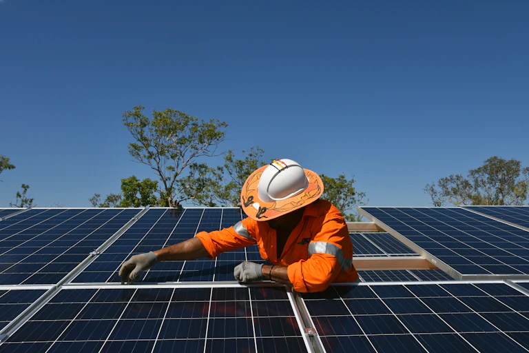 A First Nations person installs a solar panel.