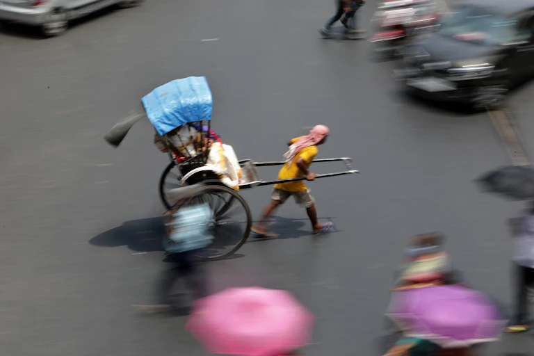 A man pulls a rickshaw across a busy intersection.