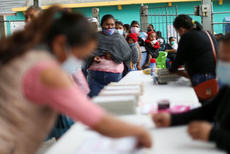 A woman in pink leans over to put her vote in the box.