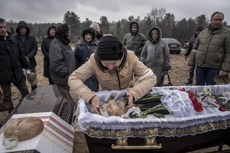 A woman leaning over a coffin.