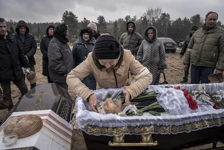 A woman leaning over a coffin.
