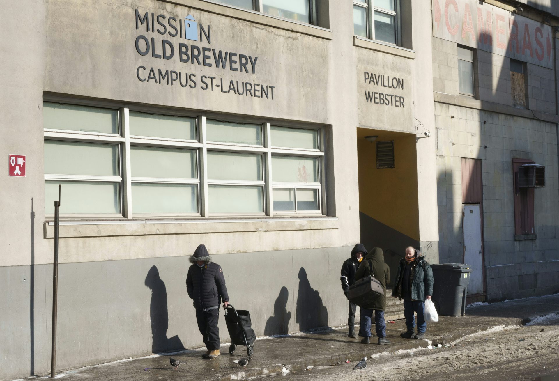 Des hommes déambulent dans la rue, avec des sacs et des valises