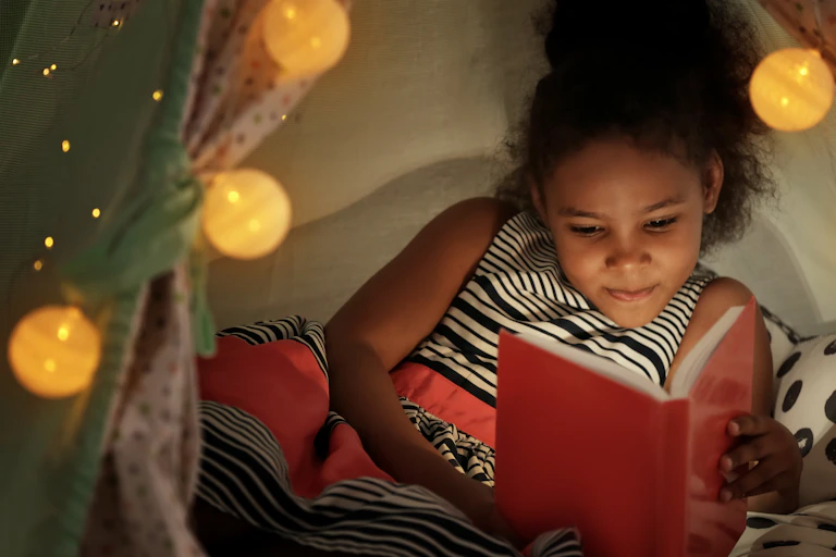 A girl seen reading inside a tent.