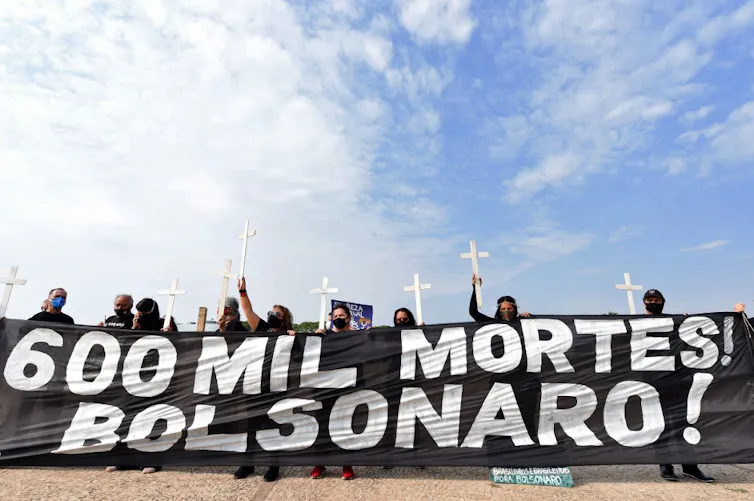 Des manifestants brandissent une bannière annonçant 600 000 morts