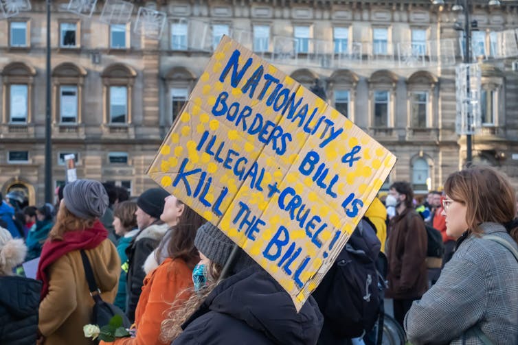 A protestor holds a sign reading'nationality and border bill is illegal and cruel. Kill the bill'.